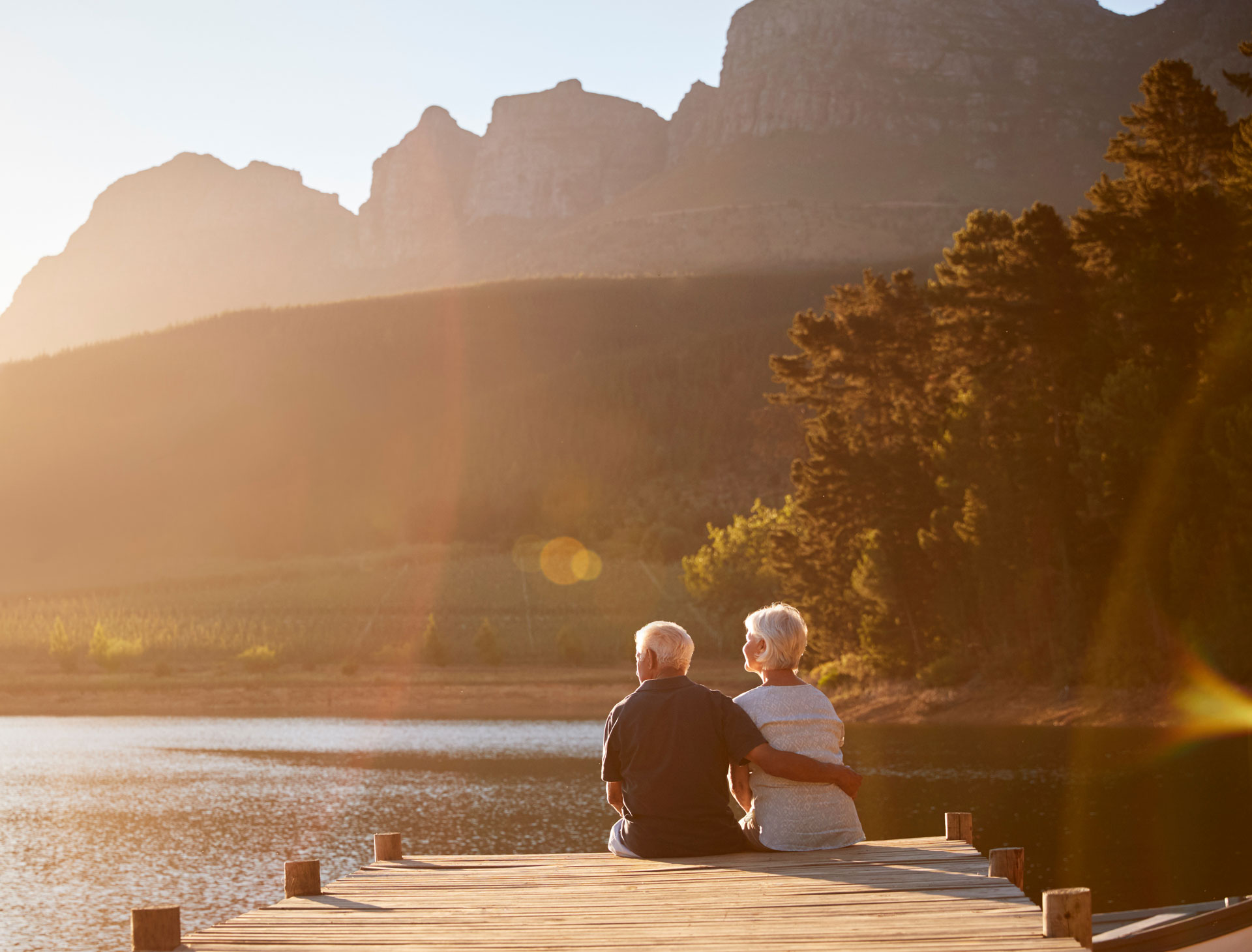 Couple enjoying a peaceful sunset while sitting on a lakeside dock, representing the calm confidence of financial security